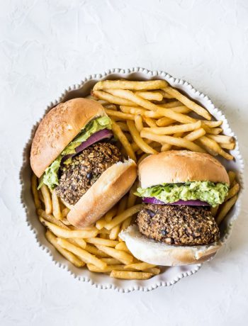 Two burgers with french fries in a dish.