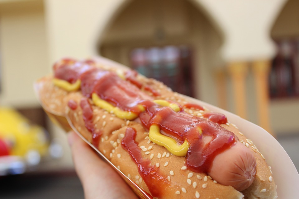 Foot long hot dog being held by someone with ketchup and mustard.