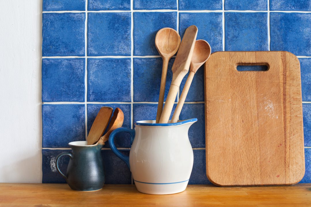 Blue blacksplash design with a cutting board and two utensil holders.