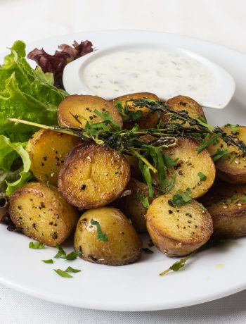 Potatoes on a plate with dipping sauce and lettuce.