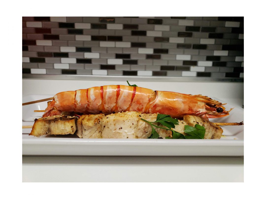 Swordfish and jumbo prawn kebabs on a countertop.