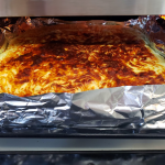 Food cooking in an oven wrapped in tin foil.