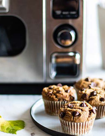 Chocolate muffins with chocolate chips on a plate next to a Sharp Countertop oven.