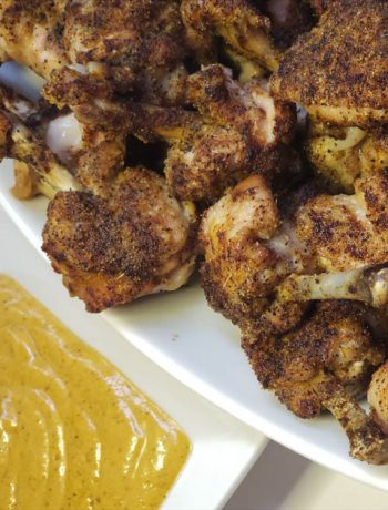 Chicken lolipops on a tray next to honey mustard dipping sauce.