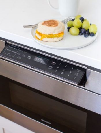 Sharp Microwave drawer underneath a breakfast sandwhich and fruit.