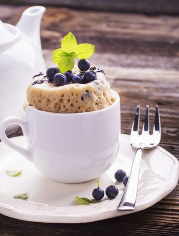 Blueberry mug cake on a plate with a fork.
