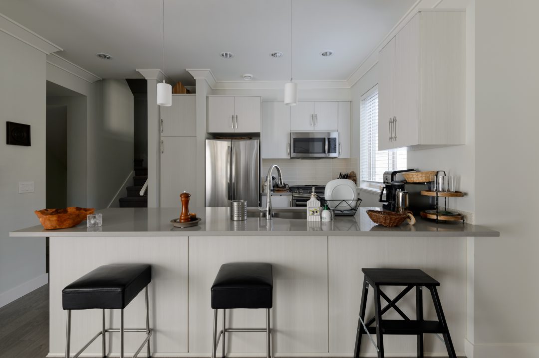 White kitchen design with three black stools.