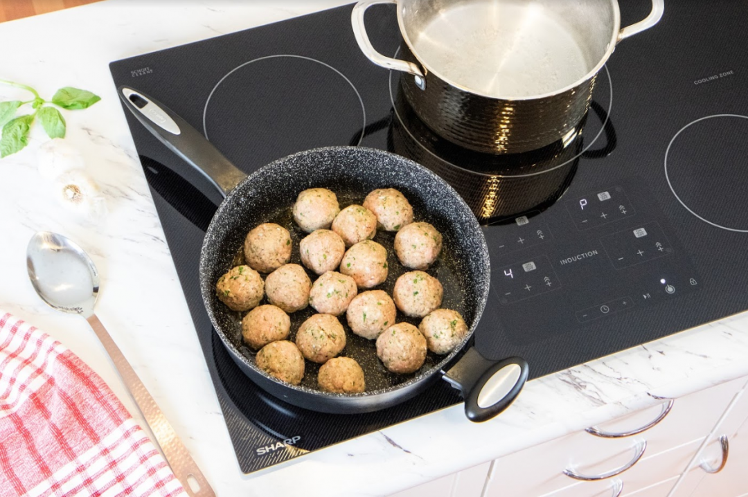 Meatballs cooking on an induction cooktop.