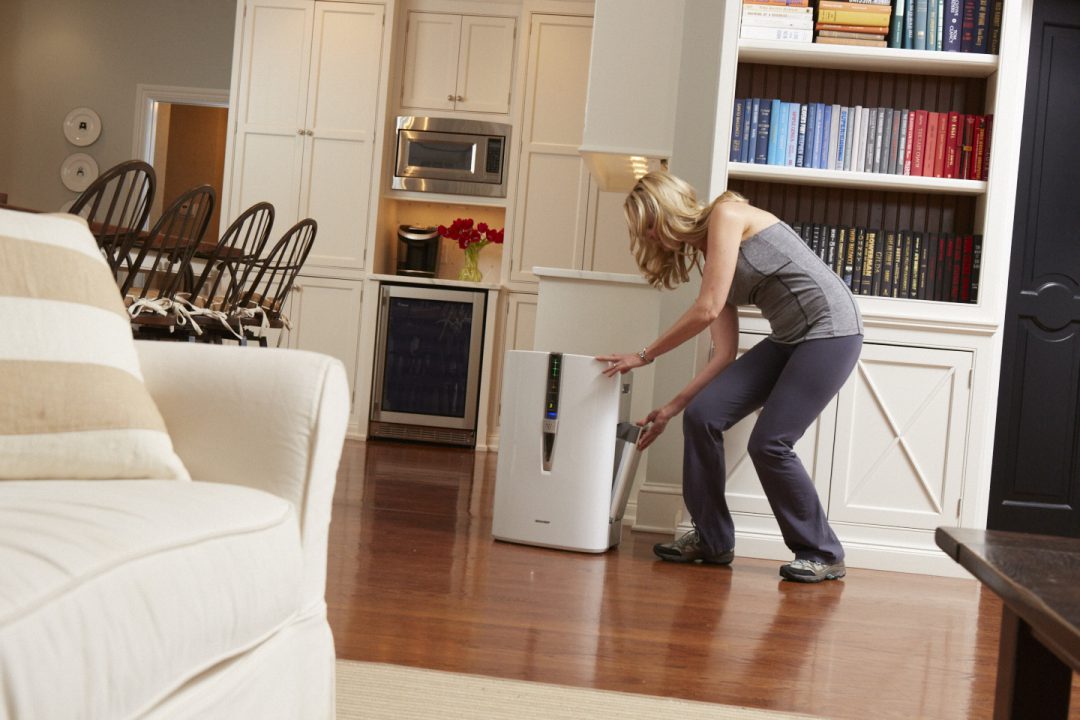 Woman adjusting air purifier in her home.