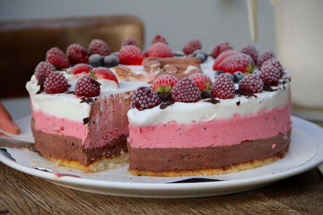 Three layered ice cream cake with strawberries on top.