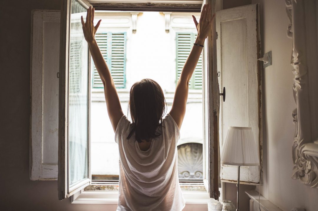 Woman stretching in front of a window.