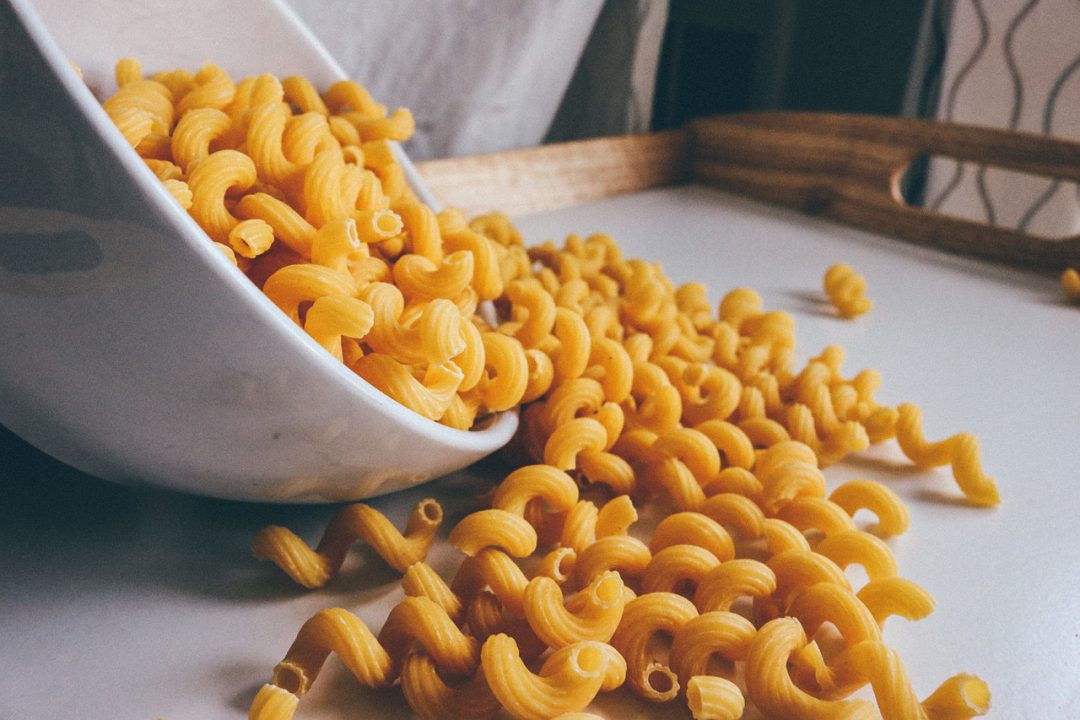 Uncooked macaroni spilling out of a bowl