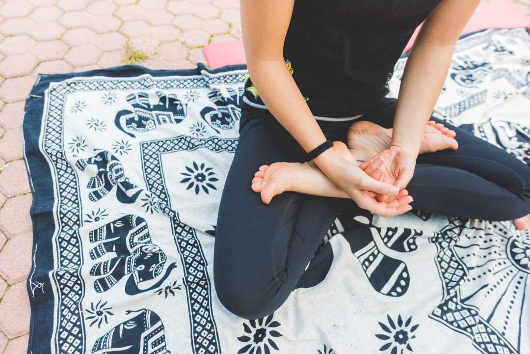 Person meditating on mat.