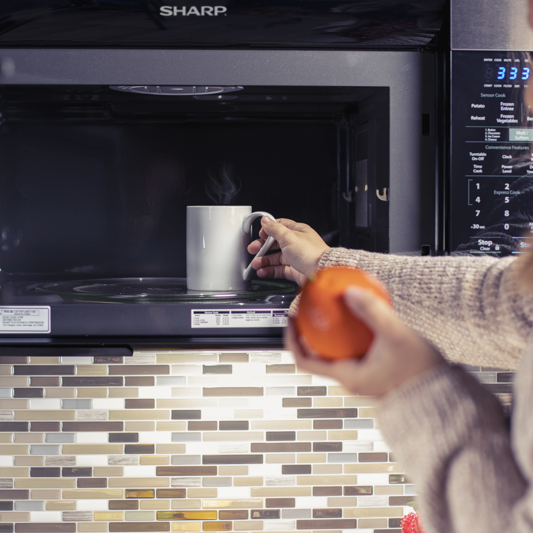person placing a mug inside a microwave