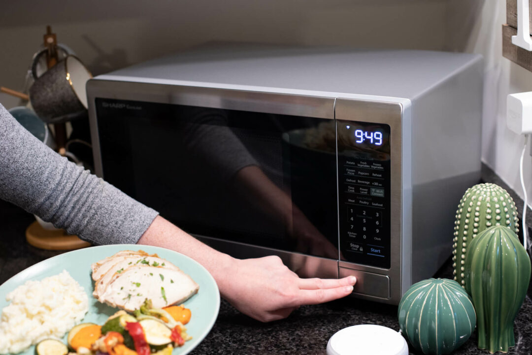 person putting plate of food in a Sharp microwave