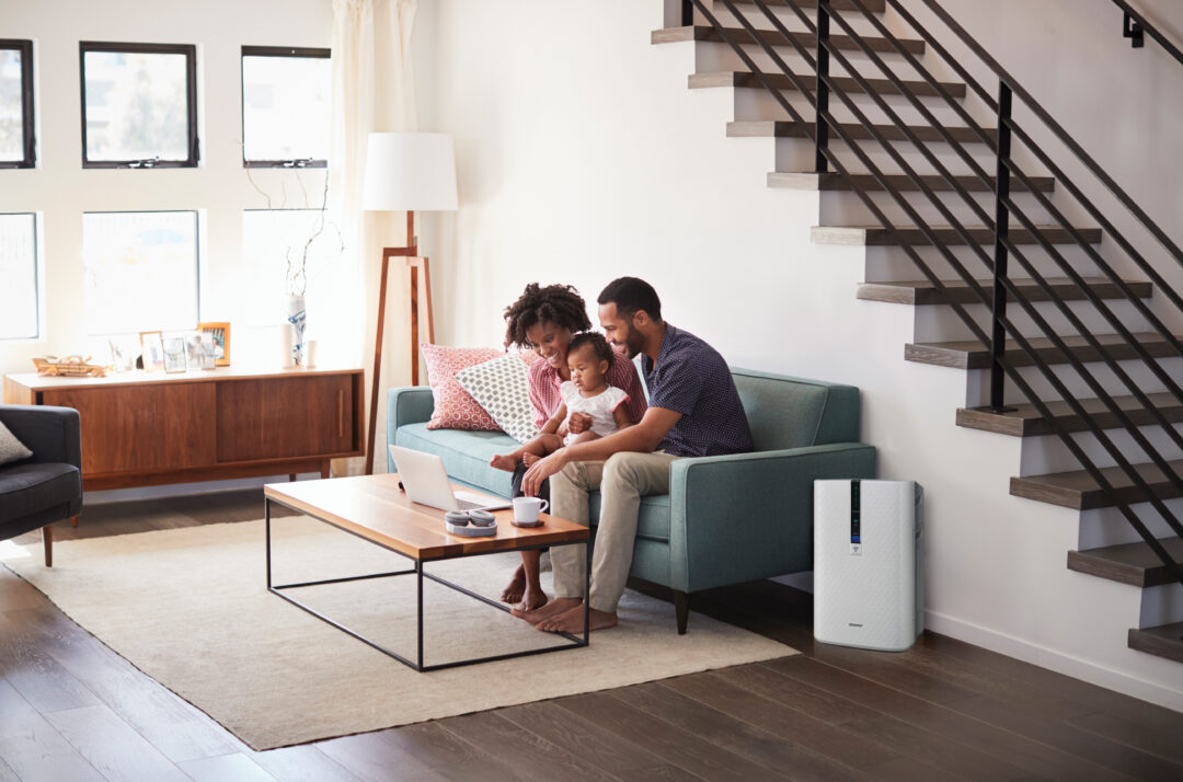 couple sitting on couch next to an air purifier