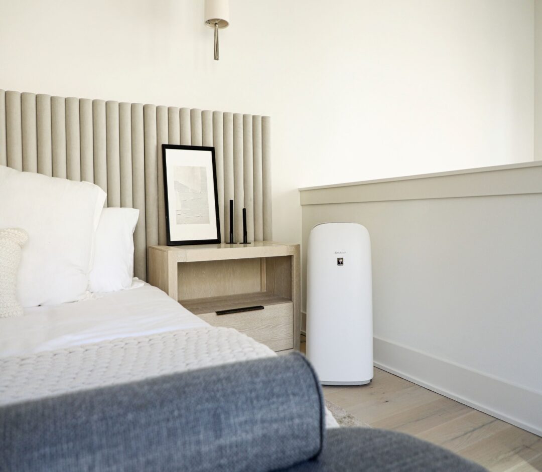 A room with a bed and Sharp air purifier