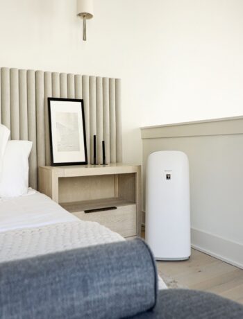 A room with a bed and Sharp air purifier