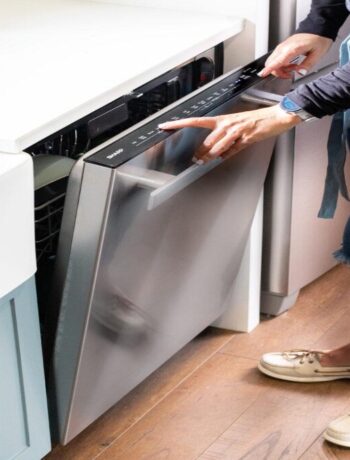 A person touching Sharp dishwasher control panel