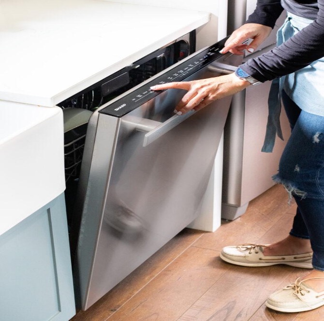 A person touching Sharp dishwasher control panel