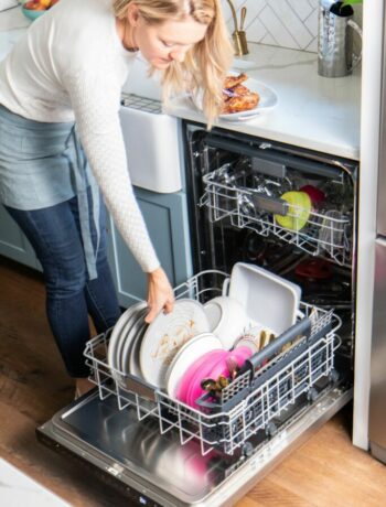 A woman loading dishes into the Sharp 24 in. Slide-In Smart Dishwasher (SDW6767HS)
