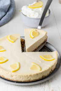 Sliced lemon cheesecake with slice being removed from the whole