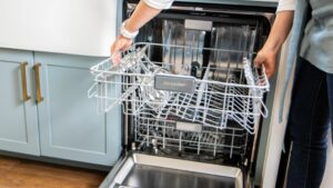 Woman lowering top rack of dishwasher