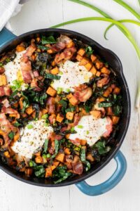 Sweet potato breakfast skillet in cast iron pan on a white background with eggs