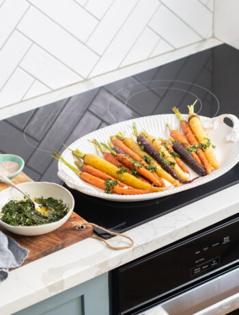 Roasted carrots on a serving tray on a sharp cooktop