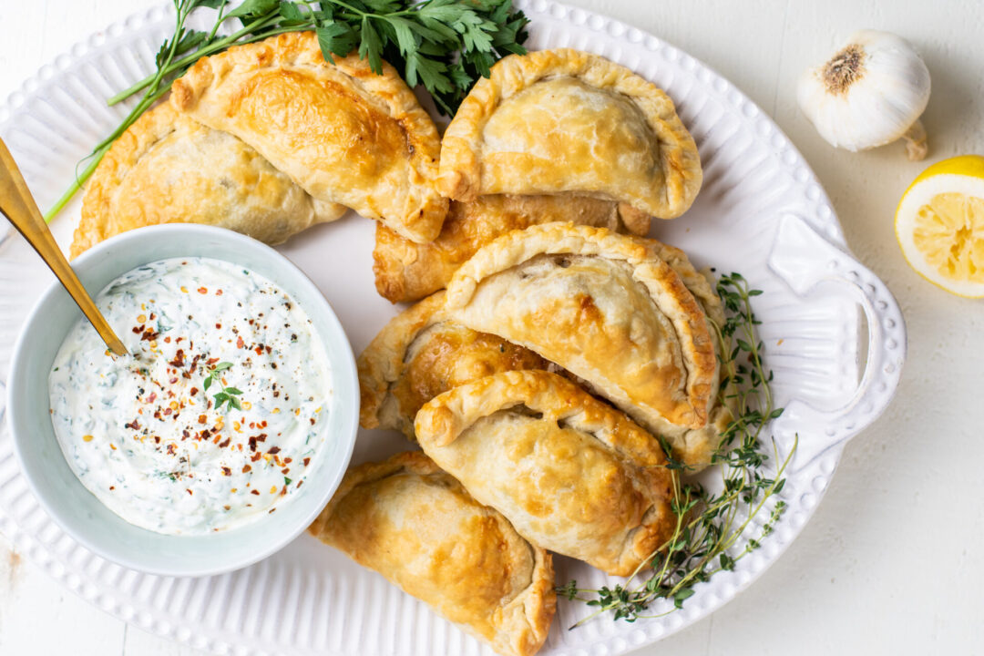 Empanadas with a chimichurri sauce on a serving platter
