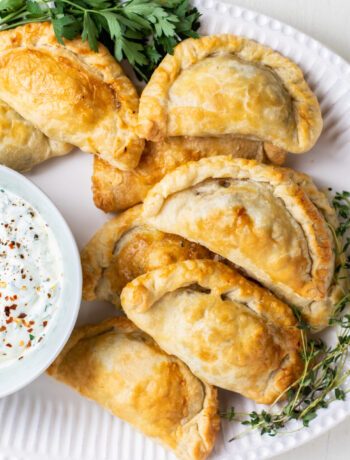 Empanadas with a chimichurri sauce on a serving platter