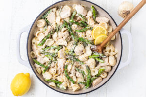 lemon chicken pasta in a dish with wooden spoon