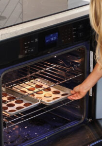 Chocolate Sandwich Cookies being placed into an oven by a woman
