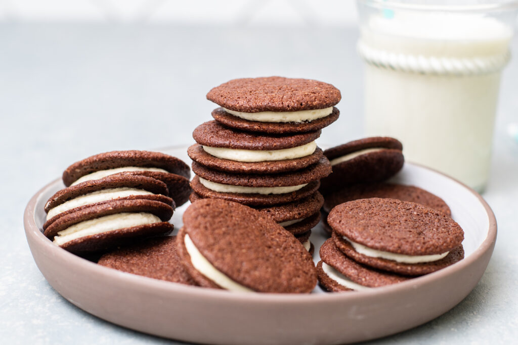 Chocolate Sandwich Cookies in a dinner bowl with a glass of milk