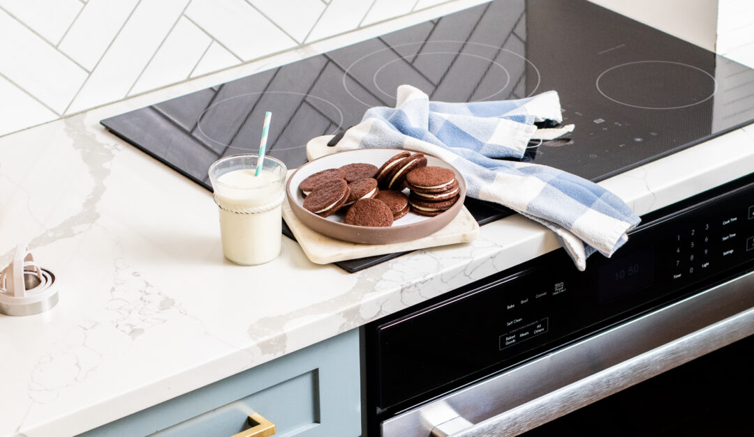 Chocolate Sandwich Cookies plated with a glass of milk on a counter