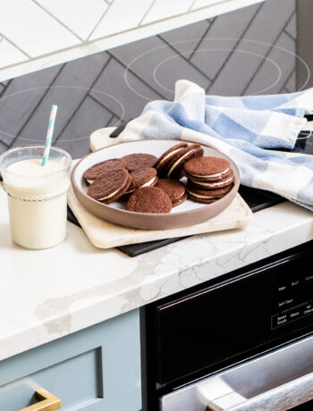 Chocolate Sandwich Cookies plated with a glass of milk on a counter