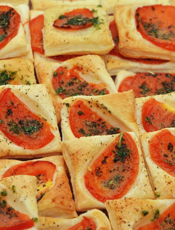 Dozens of party snacks with tomatoes alongside each other.