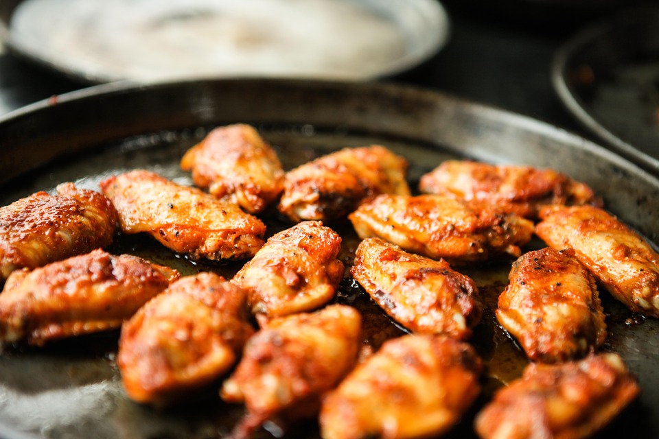 Wings in a pan on a stove.
