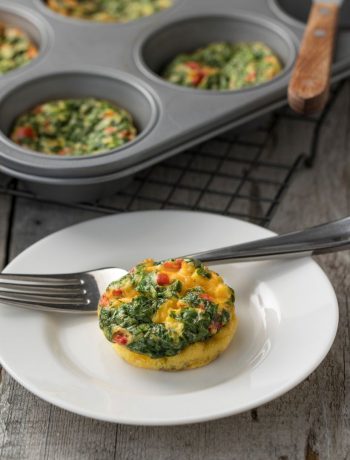 Egg Frittata on a white plate with a fork next to a cupcake tray.