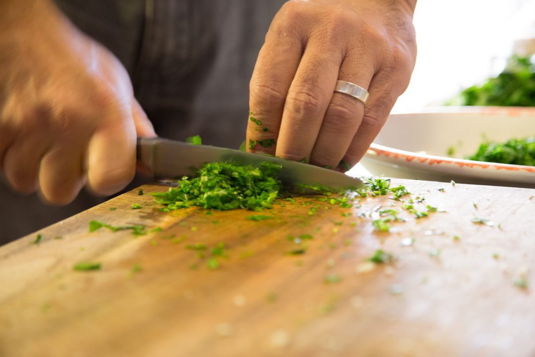 person chopping herbs on a cutting board