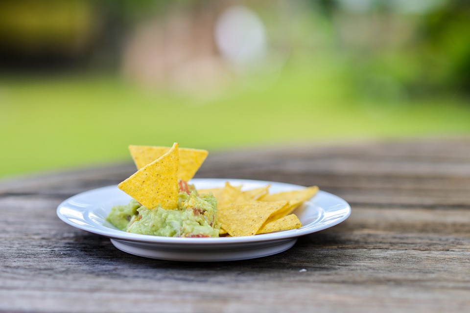 Guac and chips on a plate at an outdoor table.