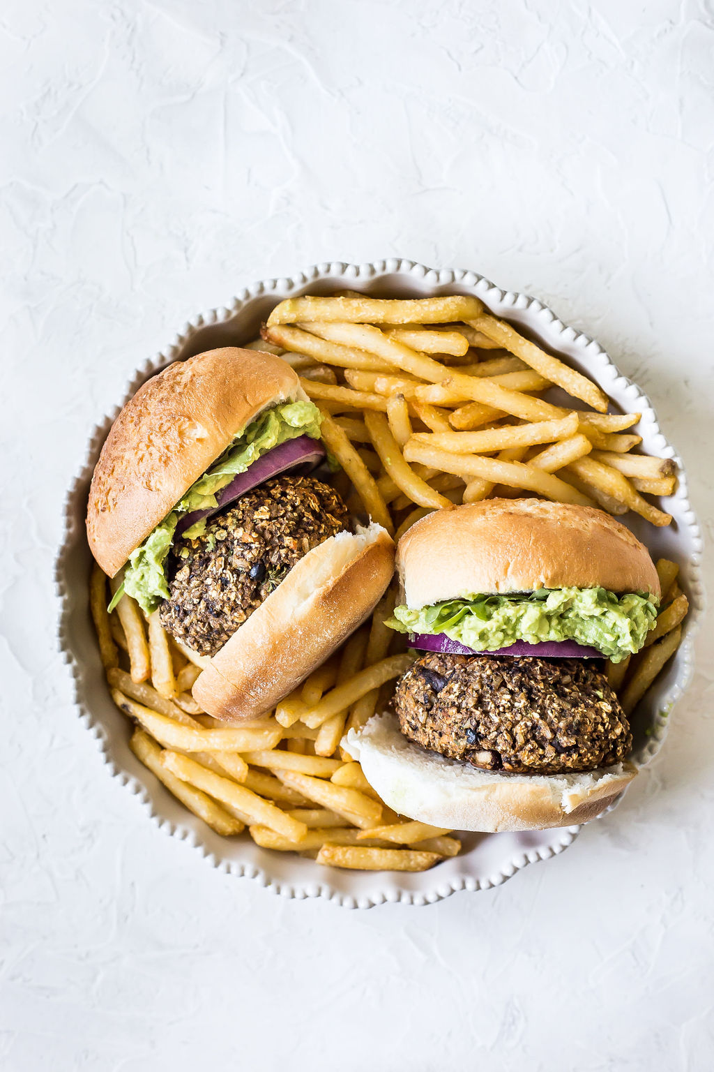 Sweet potato mushroom guac burgers in a bowl with french fries.