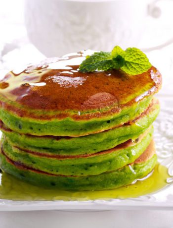 Matcha pancakes stacked upon each other on a white plate.