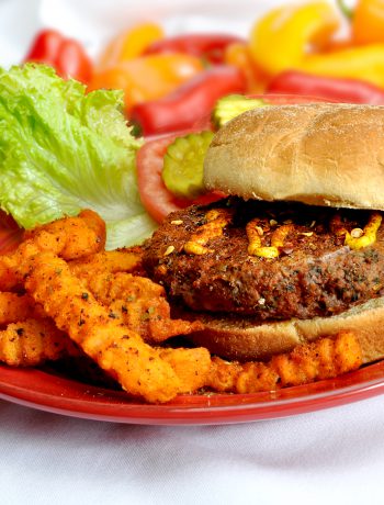 Cajun burger on a plate with sweet potato fries.