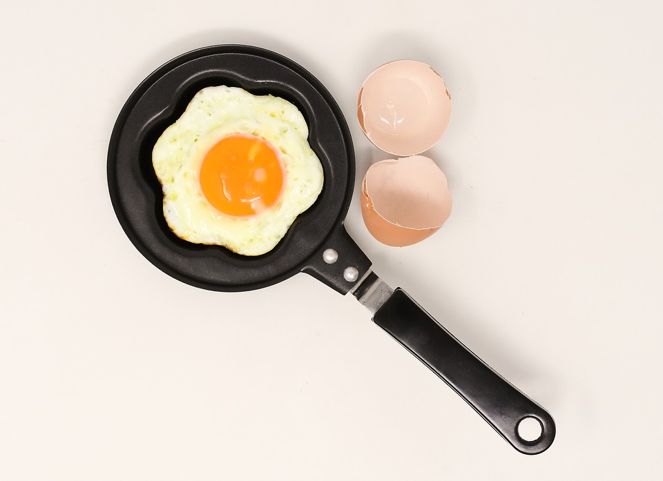 Egg in a pan next to a cracked shell.