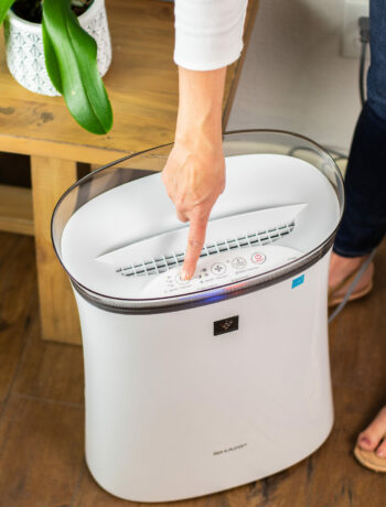 A user using the Sharp Plasmacluster Ion Air Purifier with True HEPA for Medium Rooms (FPK50UW).