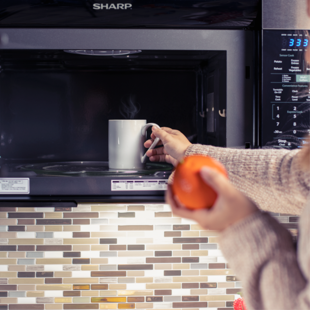 image of a person taking a mug out of a Sharp microwave