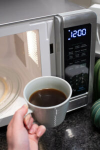 Coffee being taken out of a microwave oven