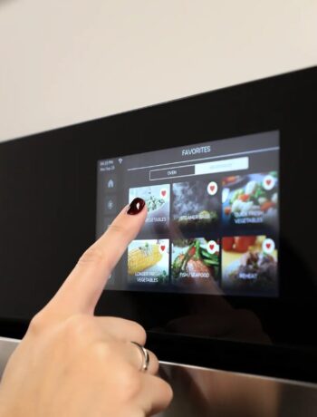 Woman using the touch screen display of the Sharp Smart Convection Wall Oven with Microwave Drawer Oven SWB3085HS