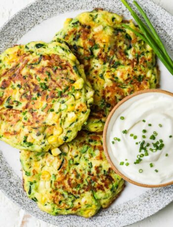 Zucchini and corn fritters plated with sour cream